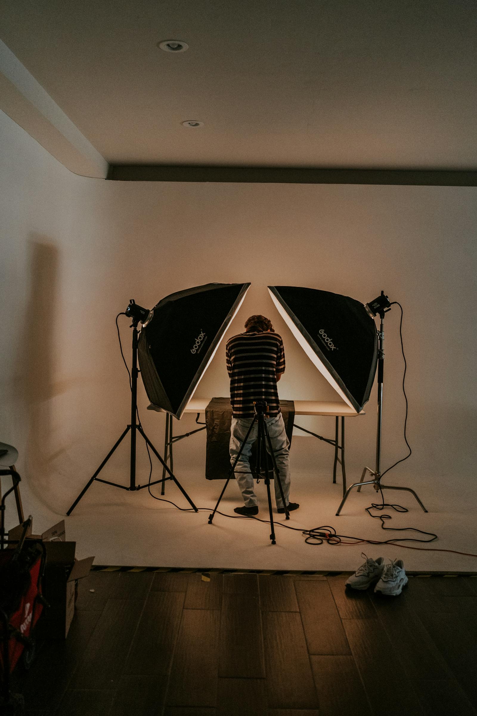 A single Profoto strobe firing through a 4×6 silk on a lagos rooftop at golden hour, two stylists holding the frame against the wind.